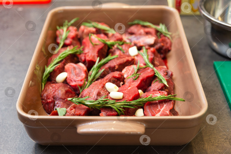 Скачать Сырая говядина с розмарином и чесноком в форме для запекания. фотосток Ozero