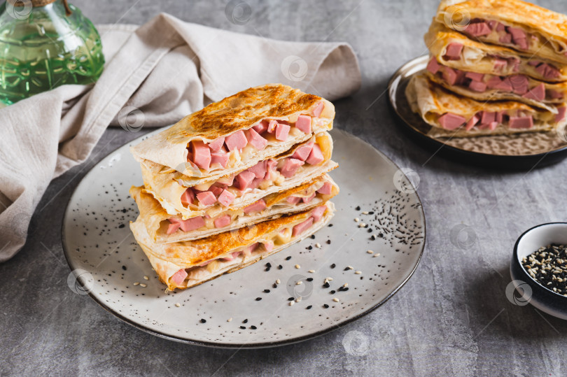 Скачать Хрустящие конвертики с колбасой и сыром в лепешках на тарелке на столе фотосток Ozero