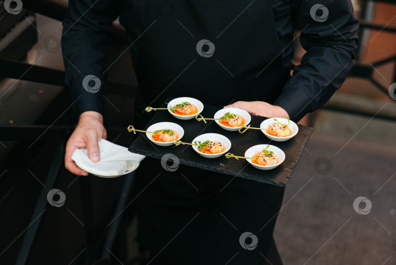 Скачать Официант, подающий изысканные закуски из креветок на мероприятии. фотосток Ozero