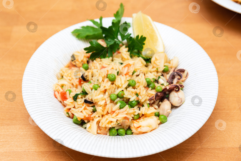 Скачать Рис с морепродуктами, зеленым горошком и лимонным гарниром. фотосток Ozero