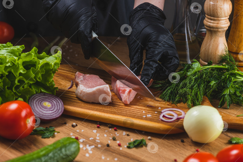 Скачать Руки в перчатках нарезают кусок мяса на доске фотосток Ozero