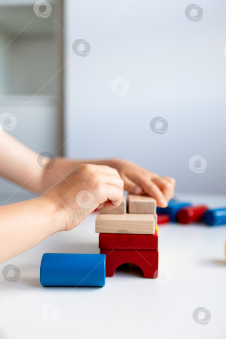 Скачать Ребенок строит разноцветные деревянные кубики на белом столе фотосток Ozero