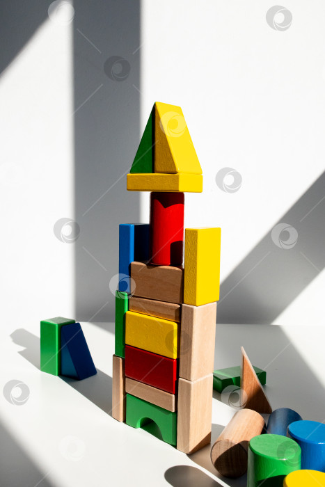 Скачать Разноцветные деревянные блоки возвышаются в залитой солнцем комнате с художественными тенями фотосток Ozero