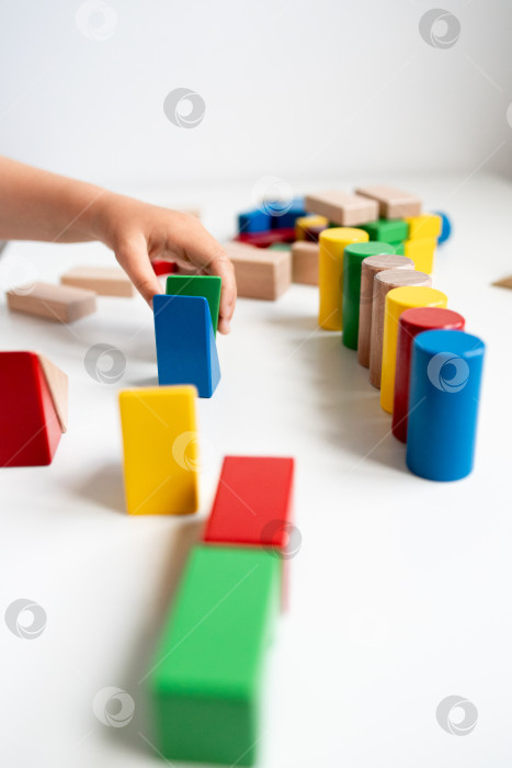 Скачать Детская рука раскладывает разноцветные деревянные кубики в игривые геометрические узоры фотосток Ozero