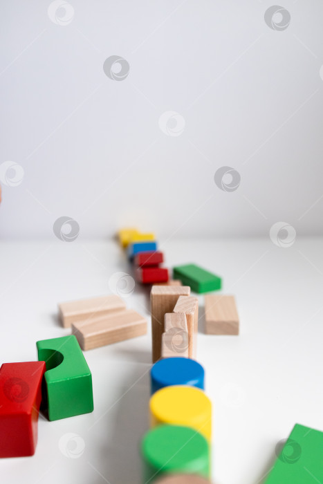 Скачать Разноцветные деревянные игрушечные кубики, выложенные креативным узором на белой поверхности фотосток Ozero