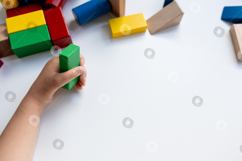 Скачать Ребенок играет с красочными деревянными строительными блоками на белом фоне фотосток Ozero