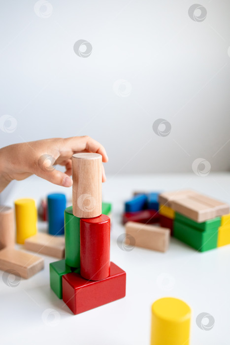 Скачать Ребенок играет с разноцветными деревянными кубиками на белой поверхности фотосток Ozero