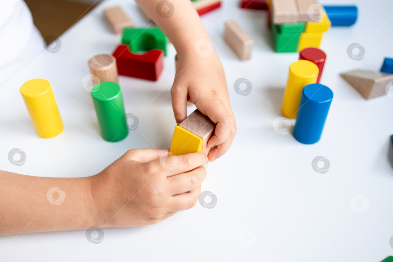 Скачать Ребенок играет с разноцветными деревянными кубиками на белом столе фотосток Ozero