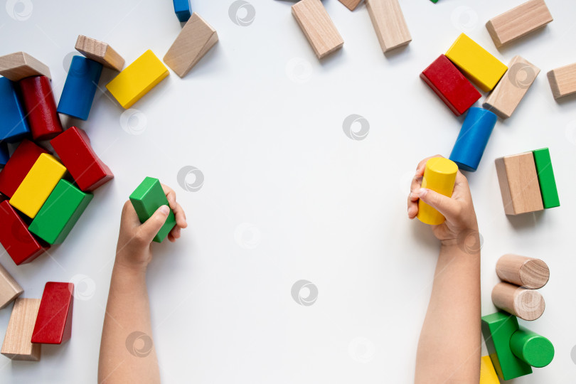 Скачать Ребенок играет с разноцветными деревянными кубиками на белом фоне фотосток Ozero