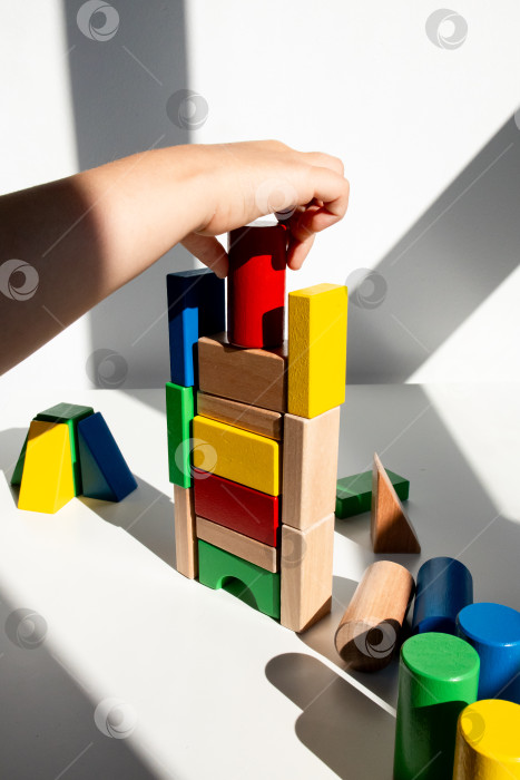 Скачать Детская ручная постройка красочной башни из деревянных блоков под солнечным светом фотосток Ozero