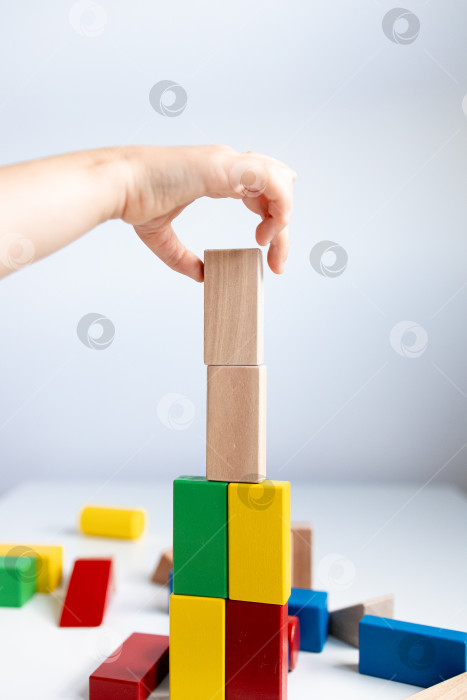 Скачать Ребенок строит красочную башню из деревянных блоков на белом столе фотосток Ozero