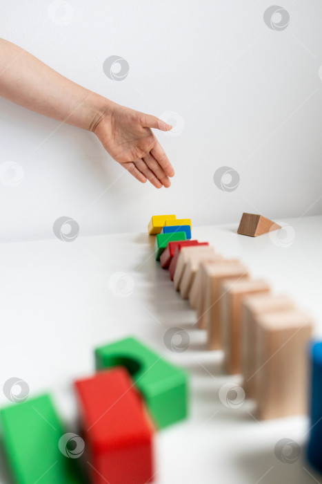 Скачать Детская рука опрокидывает разноцветные деревянные кубики по принципу домино фотосток Ozero
