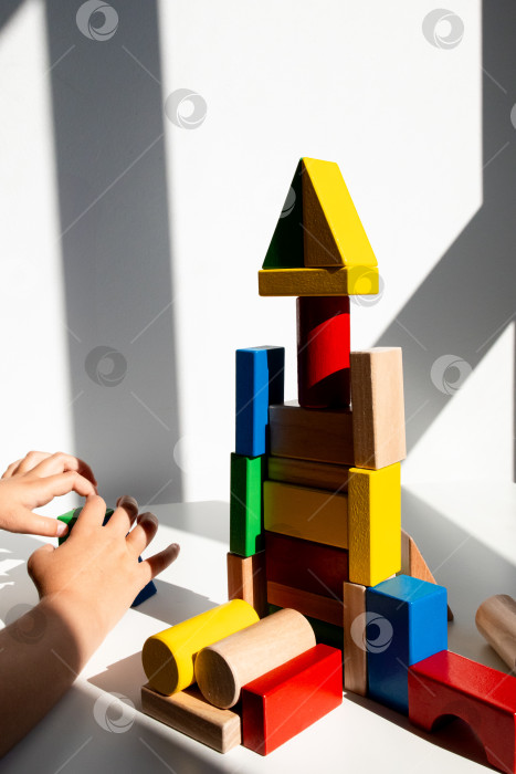Скачать Ребенок играет с разноцветными деревянными строительными блоками в залитой солнцем комнате фотосток Ozero