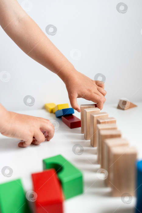 Скачать Ребенок играет с разноцветными деревянными кубиками на белой поверхности фотосток Ozero