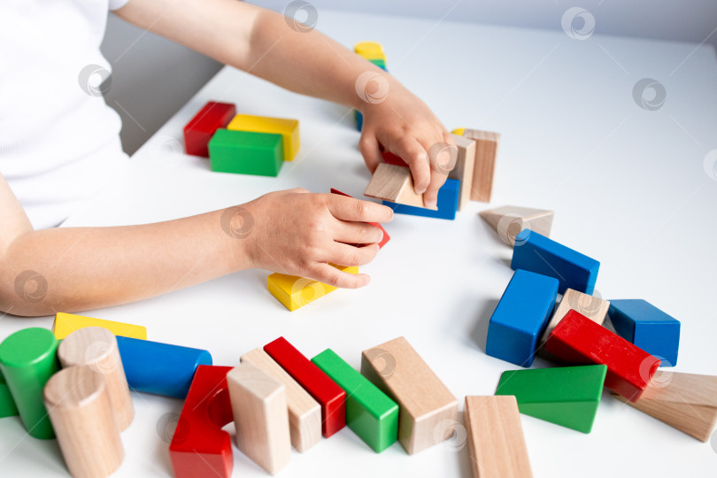 Скачать Ребенок играет с разноцветными деревянными кубиками на белом столе фотосток Ozero