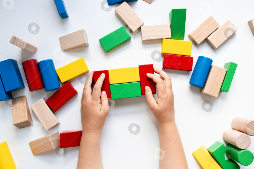 Скачать Детские ручки играют с разноцветными деревянными кубиками на белом фоне фотосток Ozero