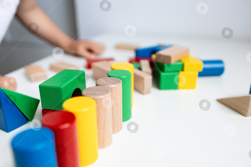 Скачать Разноцветные деревянные кубики на белом столе с детской ручкой на заднем плане фотосток Ozero