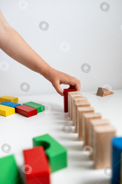 Скачать Ребенок играет с разноцветными деревянными кубиками на белой поверхности фотосток Ozero