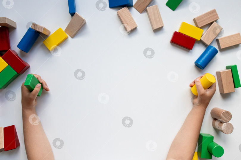 Скачать Детские руки играют с красочными строительными блоками на белом фоне фотосток Ozero