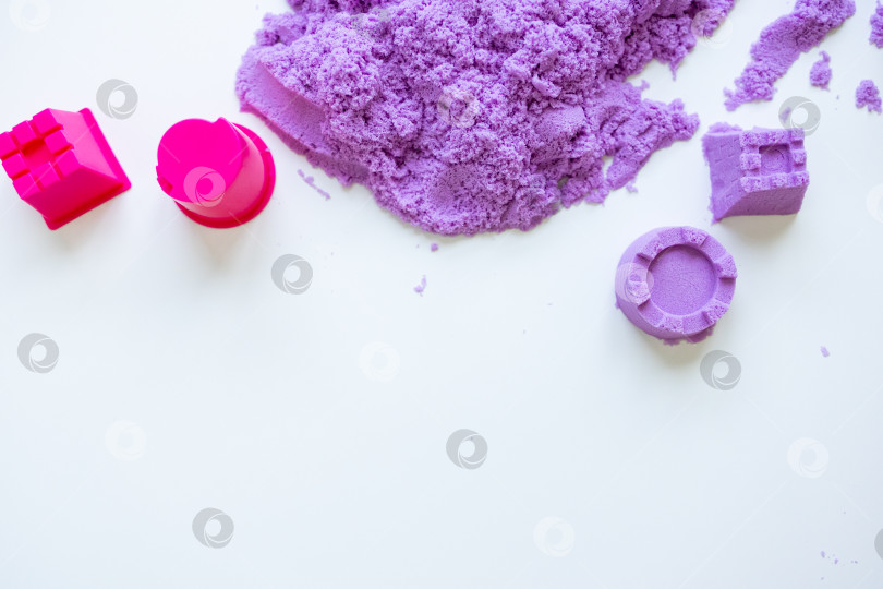 Скачать Разноцветный фиолетовый кинетический песок с формочками на белом фоне фотосток Ozero