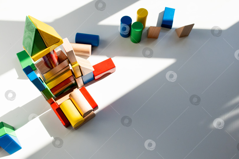 Скачать Разноцветные деревянные строительные блоки в солнечном свете на белом фоне фотосток Ozero