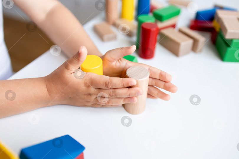 Скачать Ребенок играет с разноцветными деревянными строительными блоками на белом столе фотосток Ozero