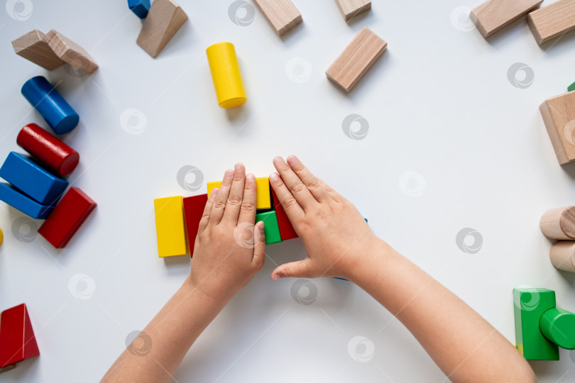 Скачать Детские ручки играют с разноцветными деревянными кубиками на белой поверхности фотосток Ozero