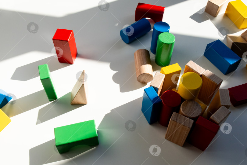 Скачать Разноцветные деревянные геометрические блоки в солнечном свете на белом фоне фотосток Ozero