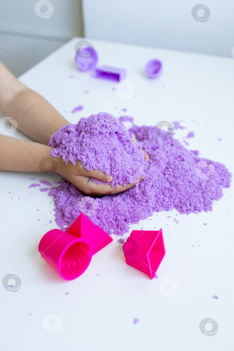 Скачать Детские ручки играют с фиолетовым кинетическим песком и лепными фигурами на столе фотосток Ozero