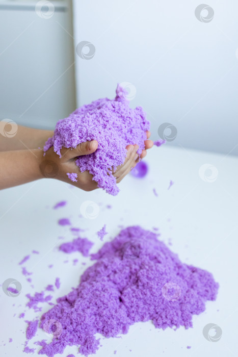 Скачать Ребенок играет с фиолетовым кинетическим песком в помещении фотосток Ozero