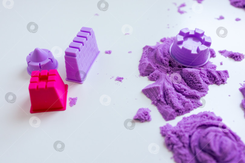 Скачать Разноцветные формочки и изделия из кинетического песка на белой поверхности фотосток Ozero