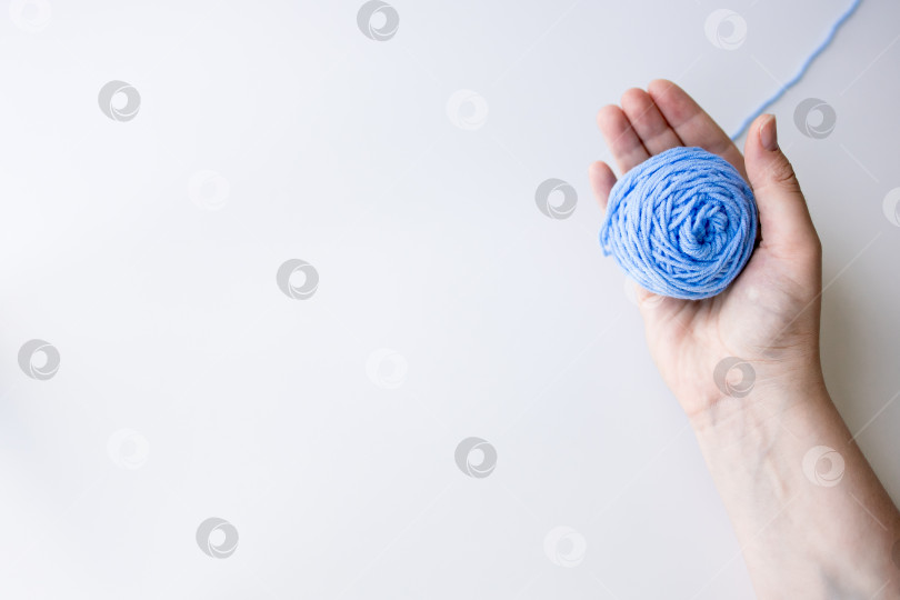 Скачать Женская рука держит клубок голубой пряжи на белом фоне фотосток Ozero