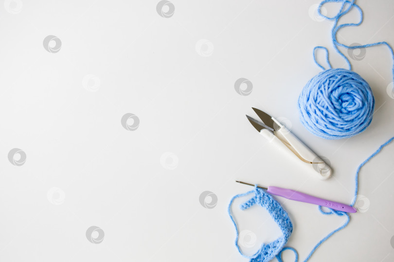 Скачать Синяя пряжа и инструменты на белом фоне. Основы вязания спицами и крючком фотосток Ozero