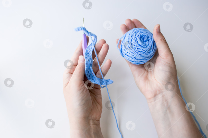 Скачать Вязание крючком своими руками из голубой пряжи на белом фоне фотосток Ozero