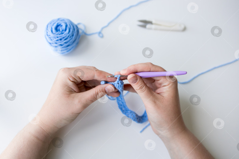 Скачать Крупный план кавказской женщины, вяжущей крючком из голубой пряжи с крючком в руке фотосток Ozero