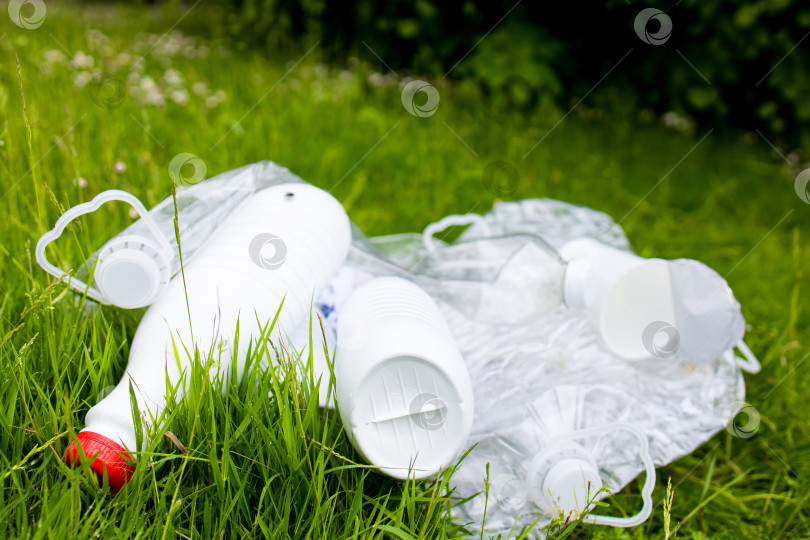 Скачать Пластиковые бутылки и упаковки, разбросанные по зеленой траве фотосток Ozero