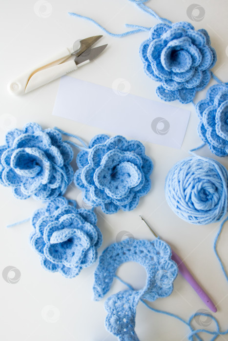 Скачать Синие цветы крючком и пряжа с инструментами на белой поверхности фотосток Ozero