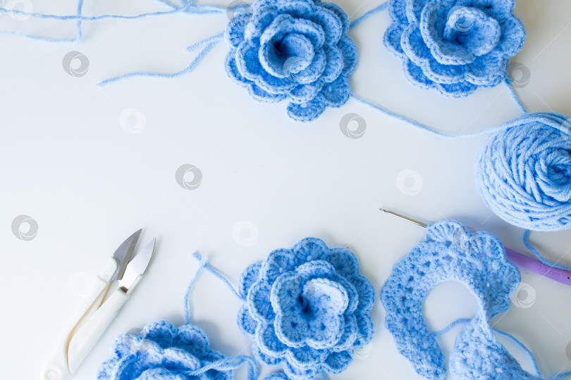 Скачать Синие цветы крючком и пряжа на белом фоне с инструментами фотосток Ozero