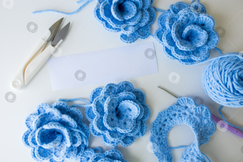 Скачать Синие цветы крючком с инструментами и пряжей на белом фоне фотосток Ozero