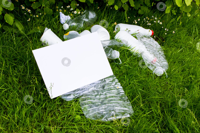 Скачать Пустой знак с изображением пластиковых отходов на траве, подчеркивающий экологические проблемы фотосток Ozero