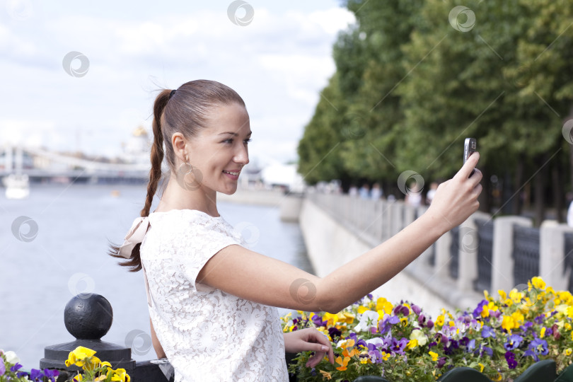 Скачать Счастливая молодая женщина фотографирует тебя на телефон фотосток Ozero