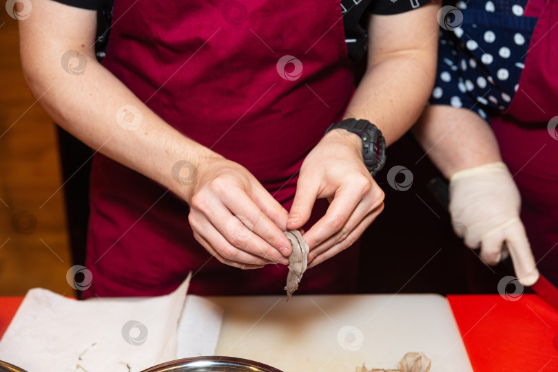 Скачать Шеф-повар чистит сырые креветки для приготовления морепродуктов. фотосток Ozero