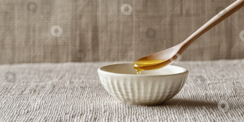 Скачать Крупный план золотистой капли рапсового масла, падающей в керамическую чашу для приготовления пищи или органического ухода за кожей. фотосток Ozero
