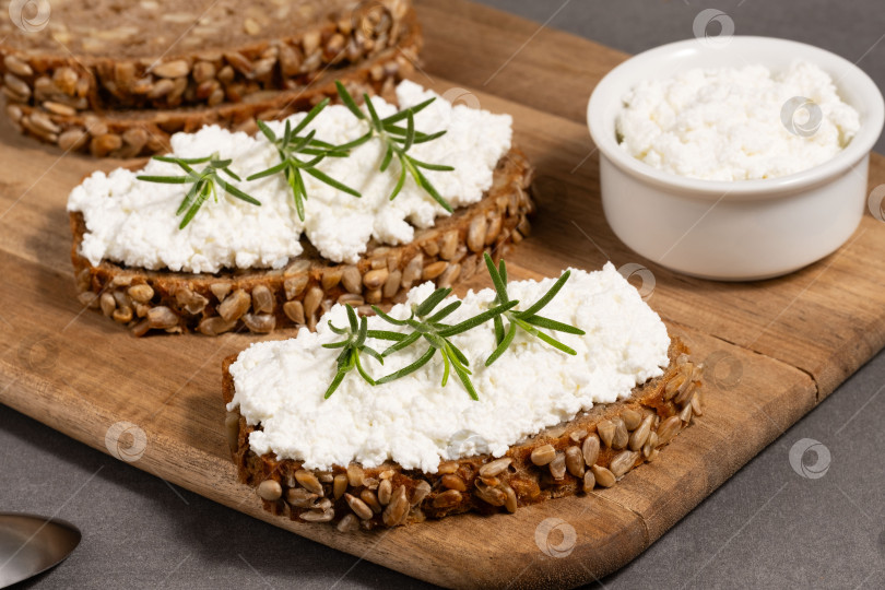 Скачать Вкусный ржаной хлеб со сливочным сыром и свежей зеленью на деревянной доске в деревенском стиле фотосток Ozero