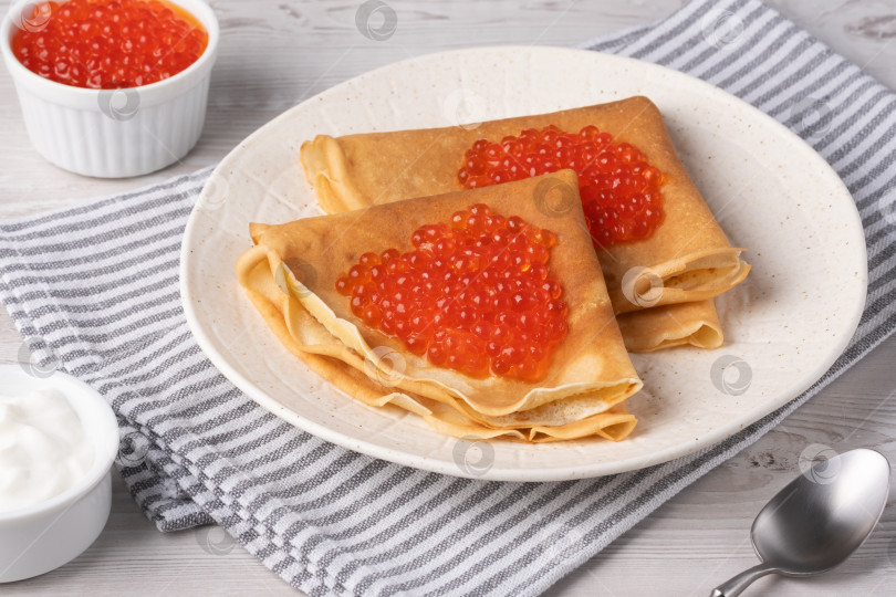 Скачать Вкусные блинчики с красной икрой подаются на уютном столе при дневном свете фотосток Ozero