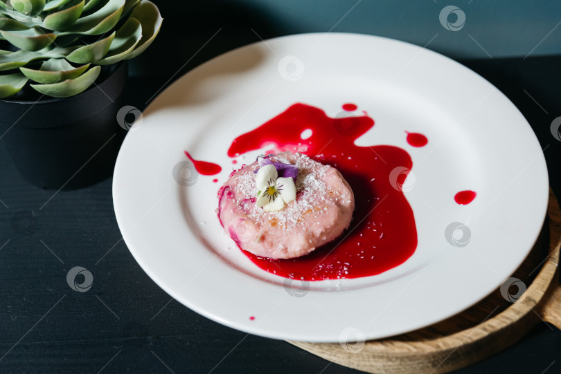 Скачать Розовый десерт с ягодным соусом и съедобными цветами. фотосток Ozero