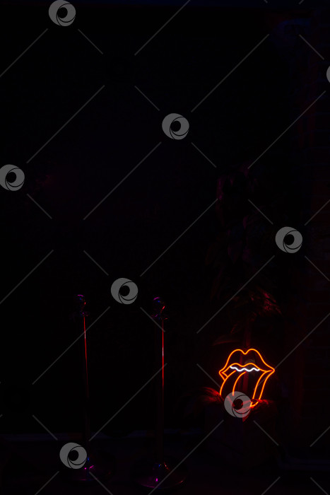 Скачать Неоновая вывеска с изображением губ и языка в темной обстановке. фотосток Ozero