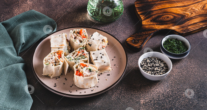 Скачать Куриное мясо, перец и огурец в соусе, завернутые в рулетики из тортильи, на тарелке с веб-баннером фотосток Ozero