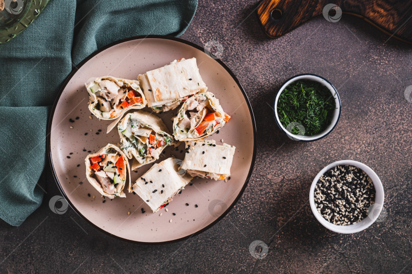 Скачать Куриное мясо, перец и огурец в соусе, завернутые в рулетики из тортильи на тарелке, вид сверху фотосток Ozero