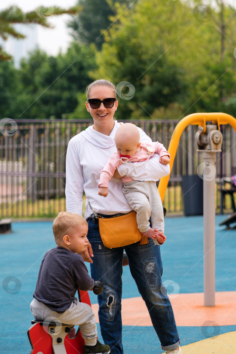 Скачать Молодая мать с детьми на детской площадке фотосток Ozero